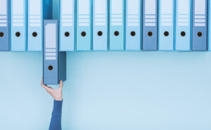 Une dizaine de classeurs bleus disposés les uns à côté des autres sur un fond bleu