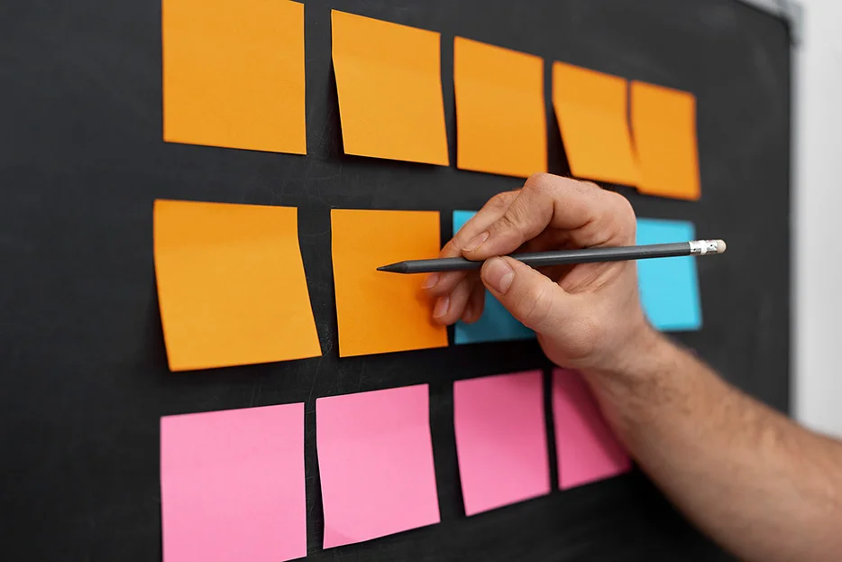 Gros plan sur un tableau noir où sont collés une dizaine de post-it colorés