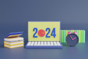 Inscription scolaire 2024 - BLog - Ordinateur indiquant l'année 2024 avec une cible à la place du 0, à côté des piles de livres et un réveil ancien