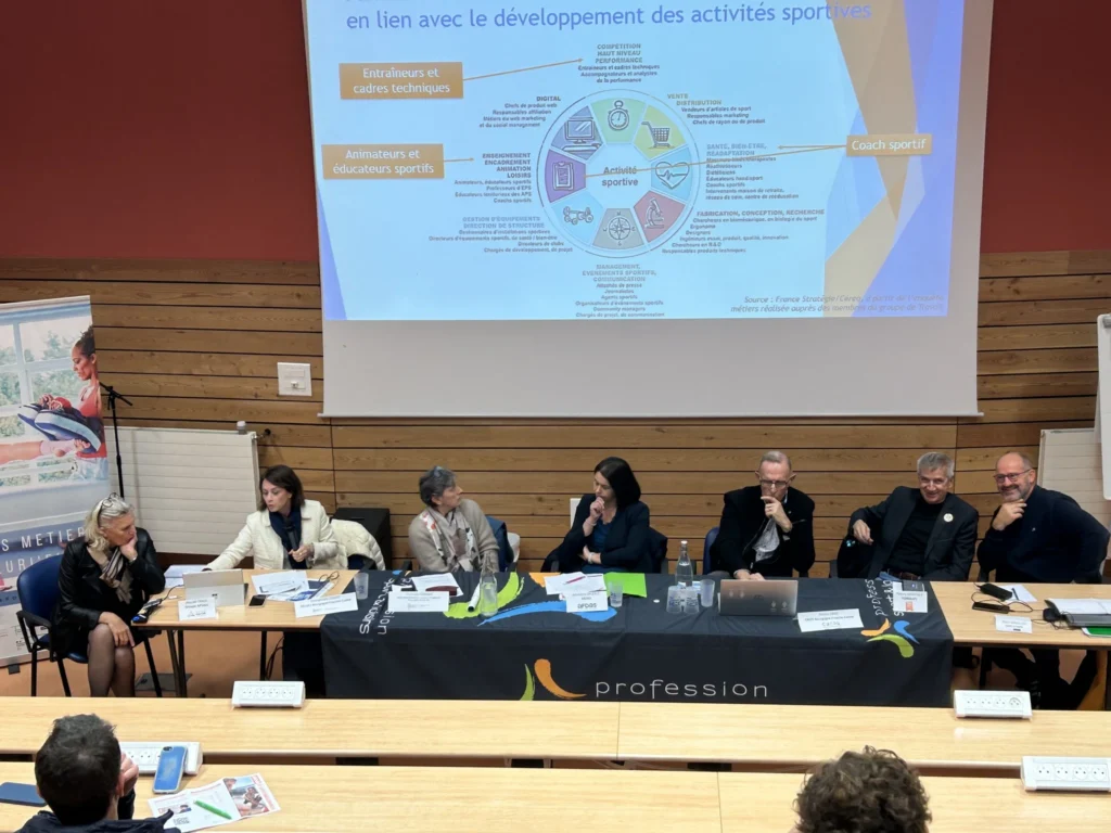 Conférence, avec table de 7 personnes assise, derrière se trouve une projection de diagramme